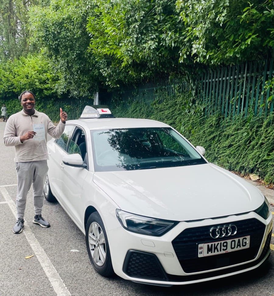 Grinning and giving a thumbs up, a learner in a stone sweatshirt and grey joggers clutches the pass certificate.
